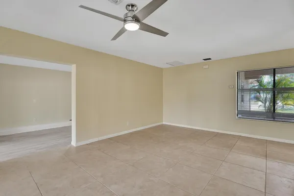an empty room with windows and fan