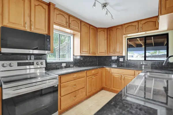 a kitchen with stainless steel appliances granite countertop a sink a stove and cabinets