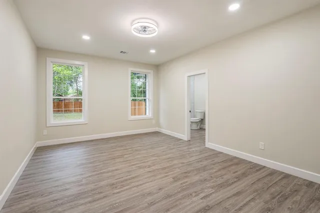 an empty room with wooden floor and windows