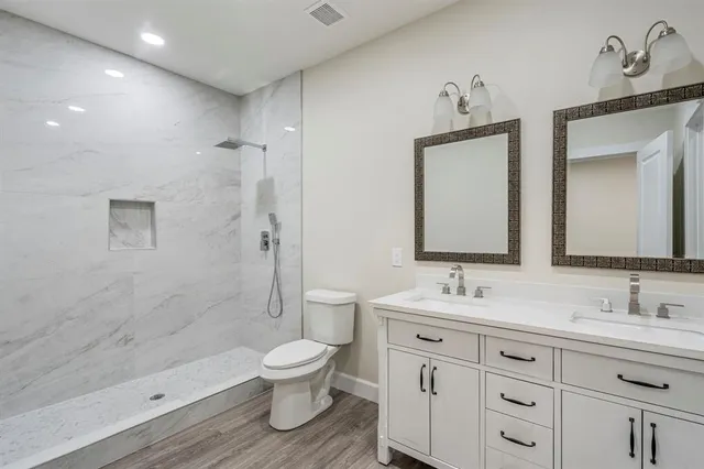 a bathroom with a double vanity sink a toilet and a shower