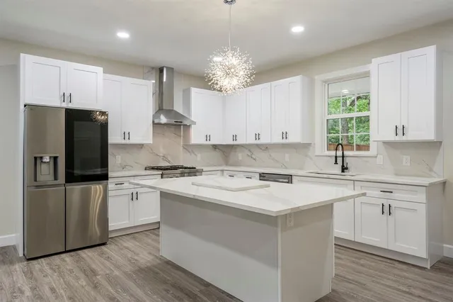 a kitchen with kitchen island granite countertop a sink cabinets stainless steel appliances and a window