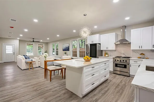 a kitchen with stainless steel appliances kitchen island granite countertop a stove and a wooden floors