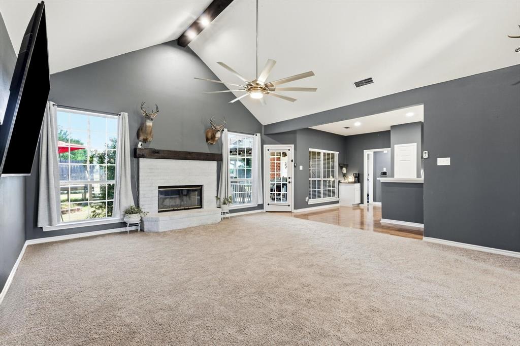1328 Pierce Road Red Oak, TX 75154 - Photo 6 of 40 Carpeted living area featuring a vaulted ceiling with exposed beam, fireplace with a white brick surround and mantel, and multiple windows