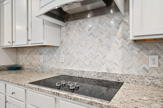 a kitchen with stainless steel appliances granite countertop a stove top oven a refrigerator a sink and white cabinets with wooden floor