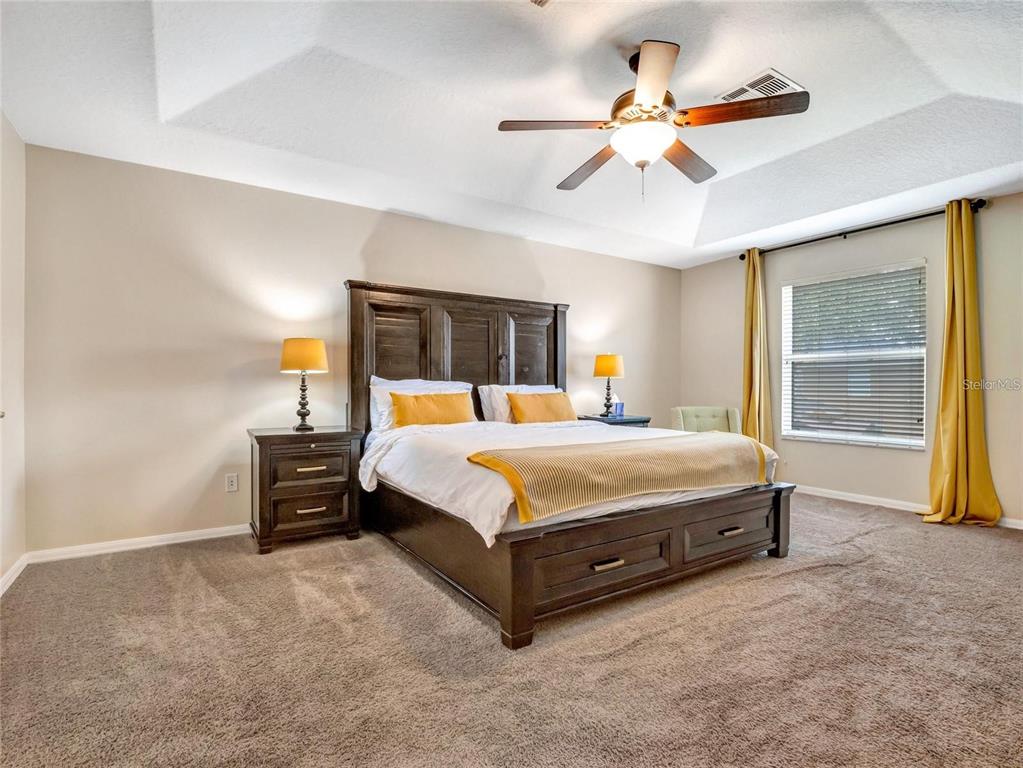 10023 Ians Ridge Road Orlando, FL 32832 - Photo 25 of 60 a spacious bedroom with a bed and a chandelier