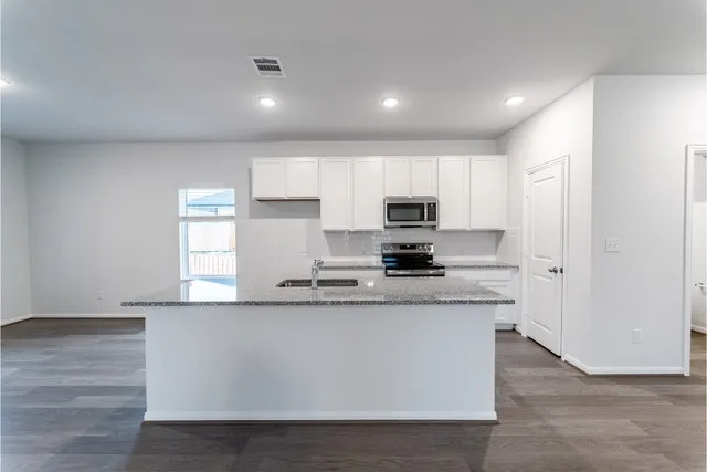 a kitchen with stainless steel appliances a sink a stove a refrigerator and cabinets