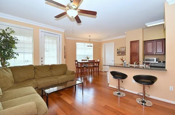 a living room with furniture kitchen view and a wooden floor