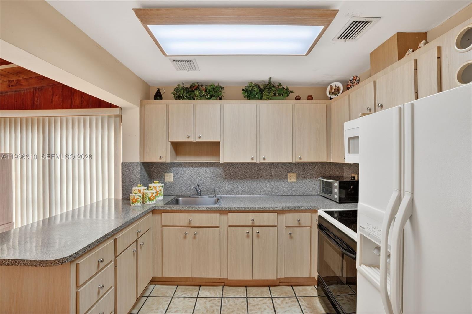 1633 Southwest 30th Avenue Miami, FL 33145 - Photo 9 of 30 a kitchen with a sink a stove a refrigerator and cabinets