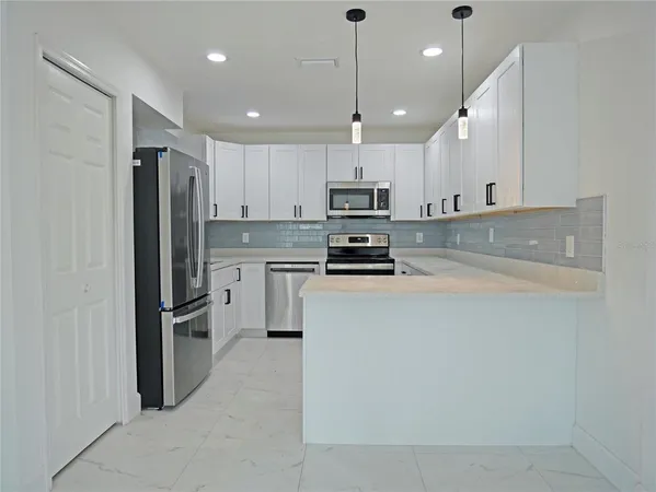 a kitchen with stainless steel appliances kitchen island a refrigerator sink and microwave