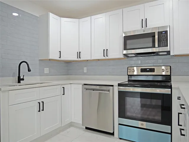 a kitchen with white cabinets and stainless steel appliances