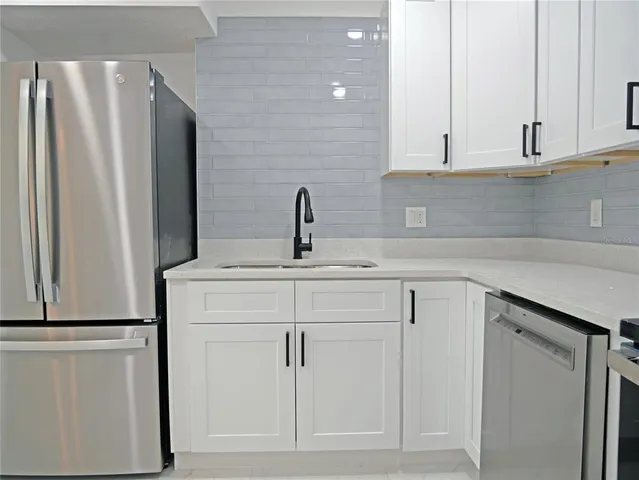 a kitchen with white cabinets and refrigerator