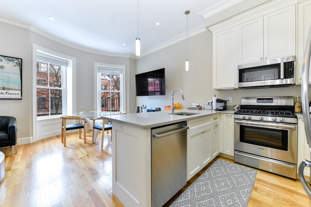 142 West Concord Street, Unit 2 Boston, MA 02118 - Photo 6 of 18 a kitchen with stainless steel appliances granite countertop a stove top oven a sink dishwasher a dining table and chairs with wooden floor