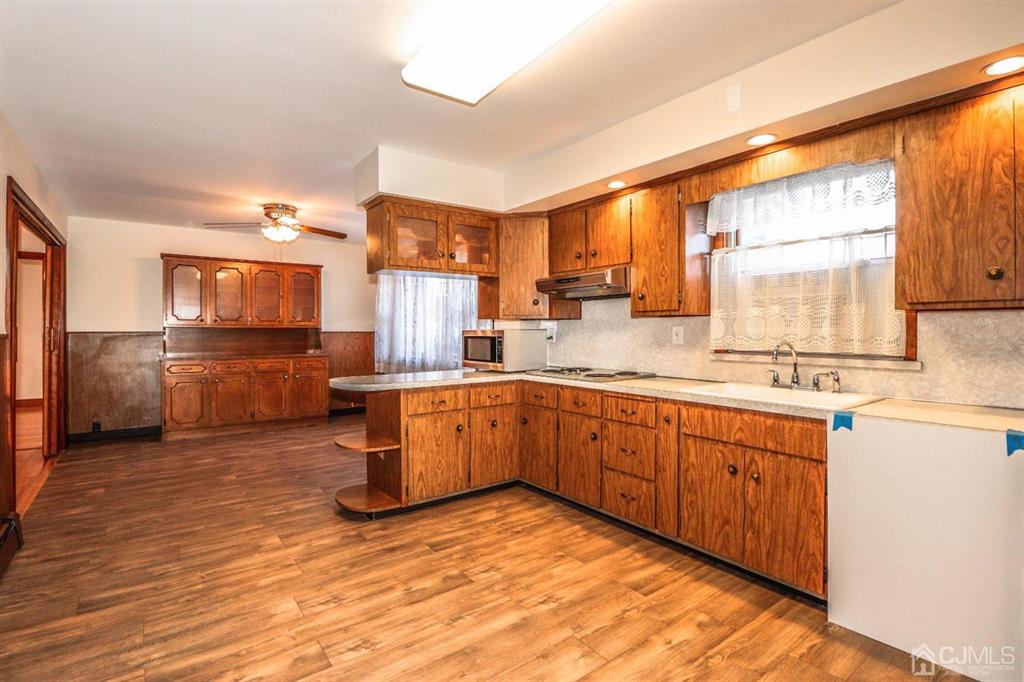 a kitchen with stainless steel appliances granite countertop a sink cabinets and wooden floor