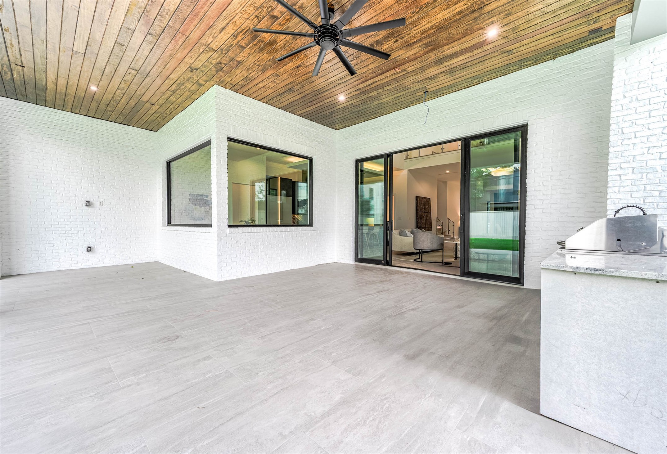 207 West 33rd Street Houston, TX 77018 - Photo 41 of 50 Covered patio with concrete tile flooring, prewired for Cat6, sound, and TV, featuring 12-foot glass slidEnjoy a outdoor kitchen featuring a 42-inch grill, granite tops, stainless steel sink, and dual stainless built-in trash bins.ing doors.