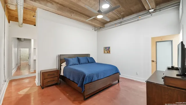 a bedroom with a bed and a flat tv screen on wall