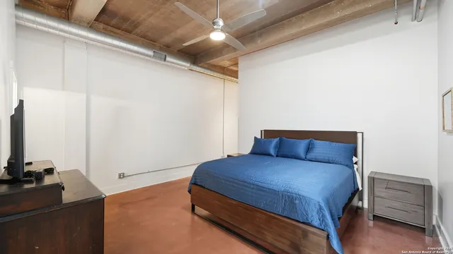 a bedroom with a bed and a flat tv screen on a dresser