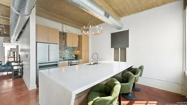 a kitchen with stainless steel appliances kitchen island granite countertop a refrigerator a stove and a dining table with wooden floor