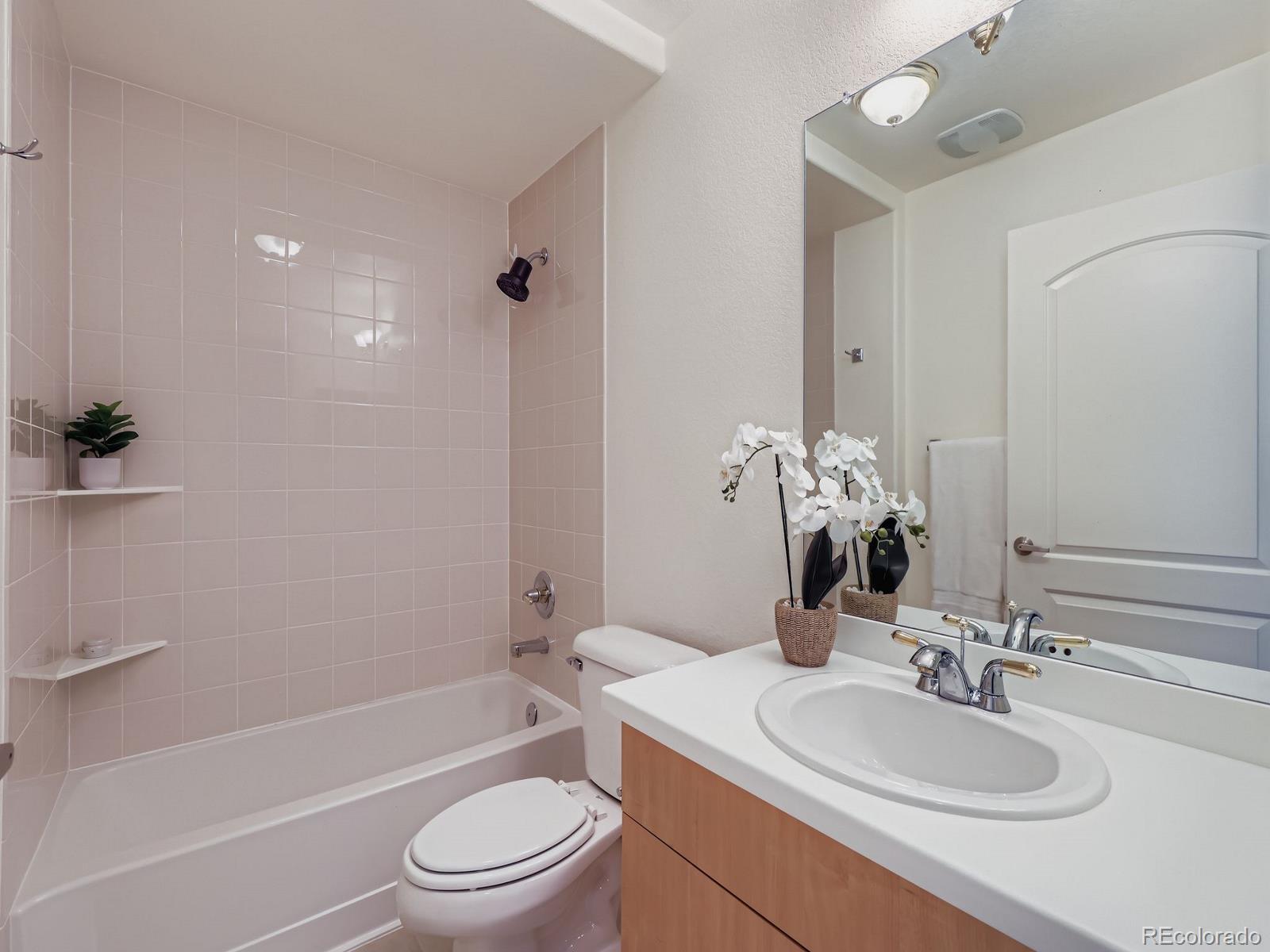8578 Gold Peak Drive, Unit D Highlands Ranch, CO 80130 - Photo 13 of 50 a bathroom with a toilet a sink a mirror a bathtub and vanity