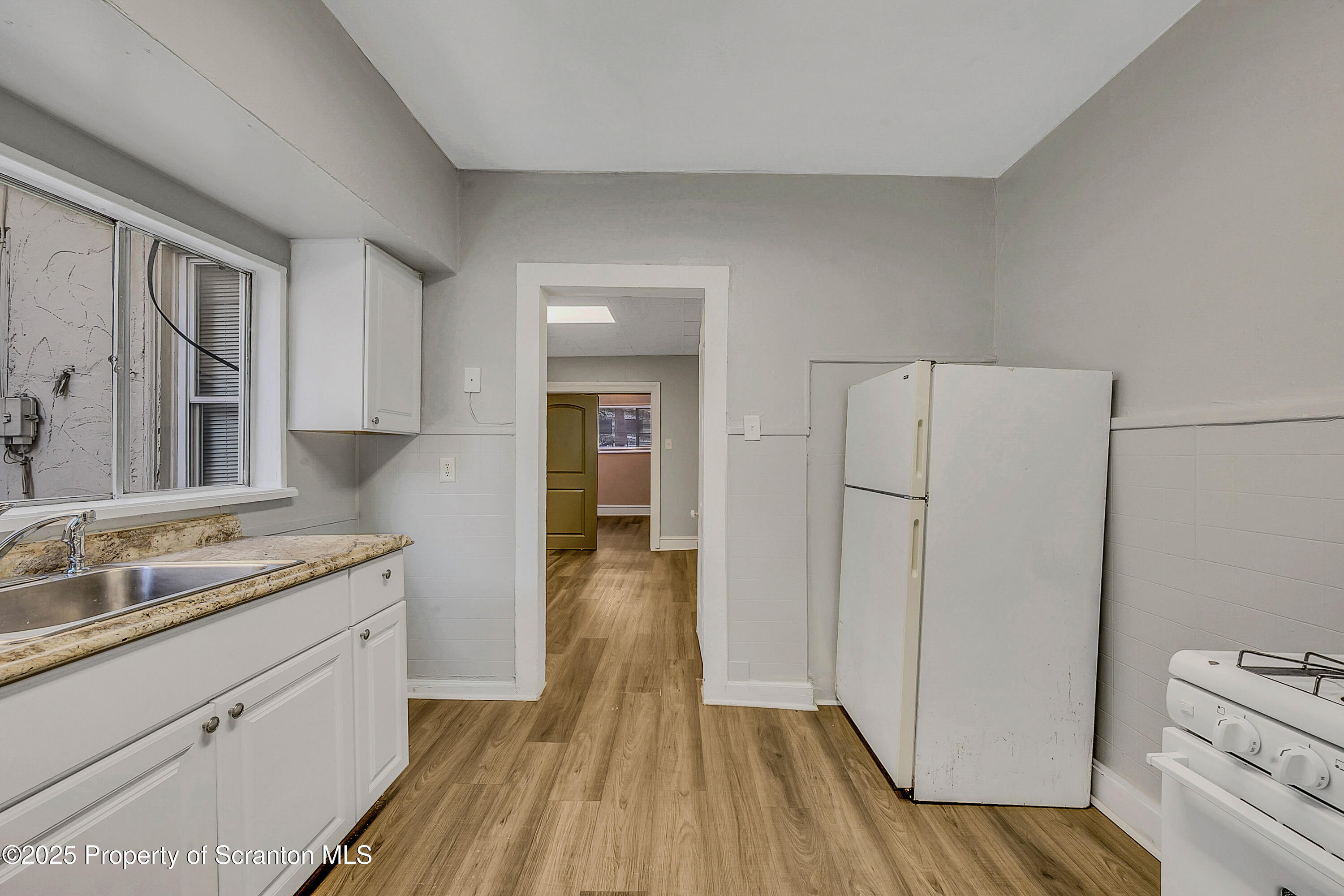 1007 Washburn Street, Unit 1 Scranton, PA 18504 - Photo 10 of 14 a kitchen with white cabinets and wooden floor