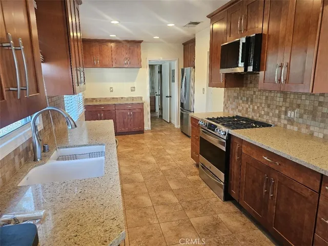 a kitchen with stainless steel appliances granite countertop a stove a sink and a microwave
