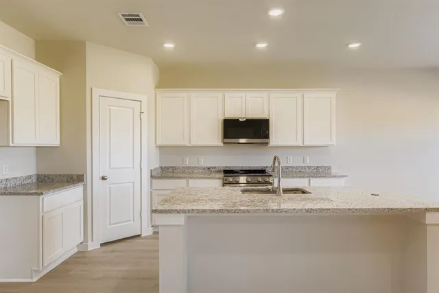 a kitchen with granite countertop white cabinets and stainless steel appliances