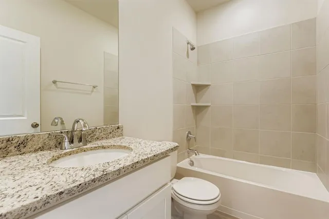 a bathroom with a granite countertop toilet a sink and a bathtub