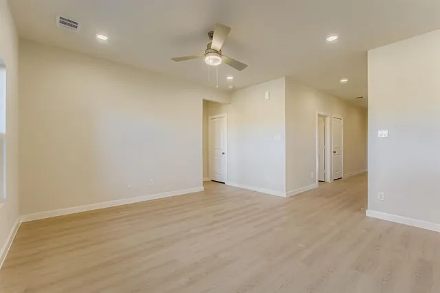 an empty room with wooden floor and a ceiling fan