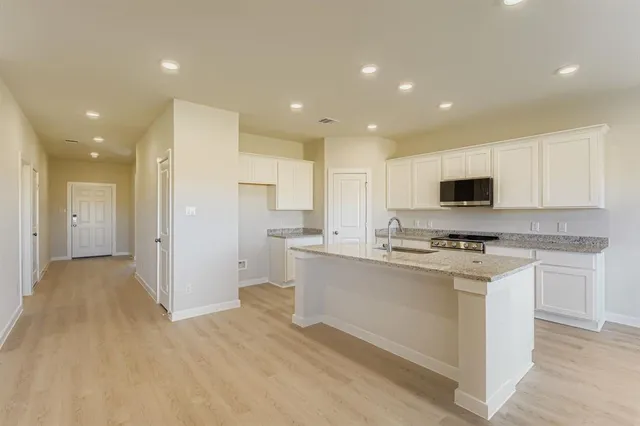 a kitchen with stainless steel appliances granite countertop a stove top oven a sink and a refrigerator