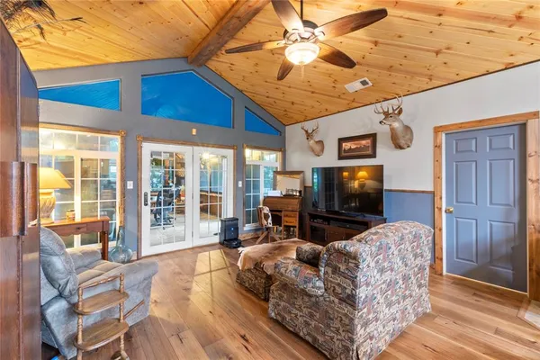 a living room with furniture a flat screen tv and floor to ceiling window