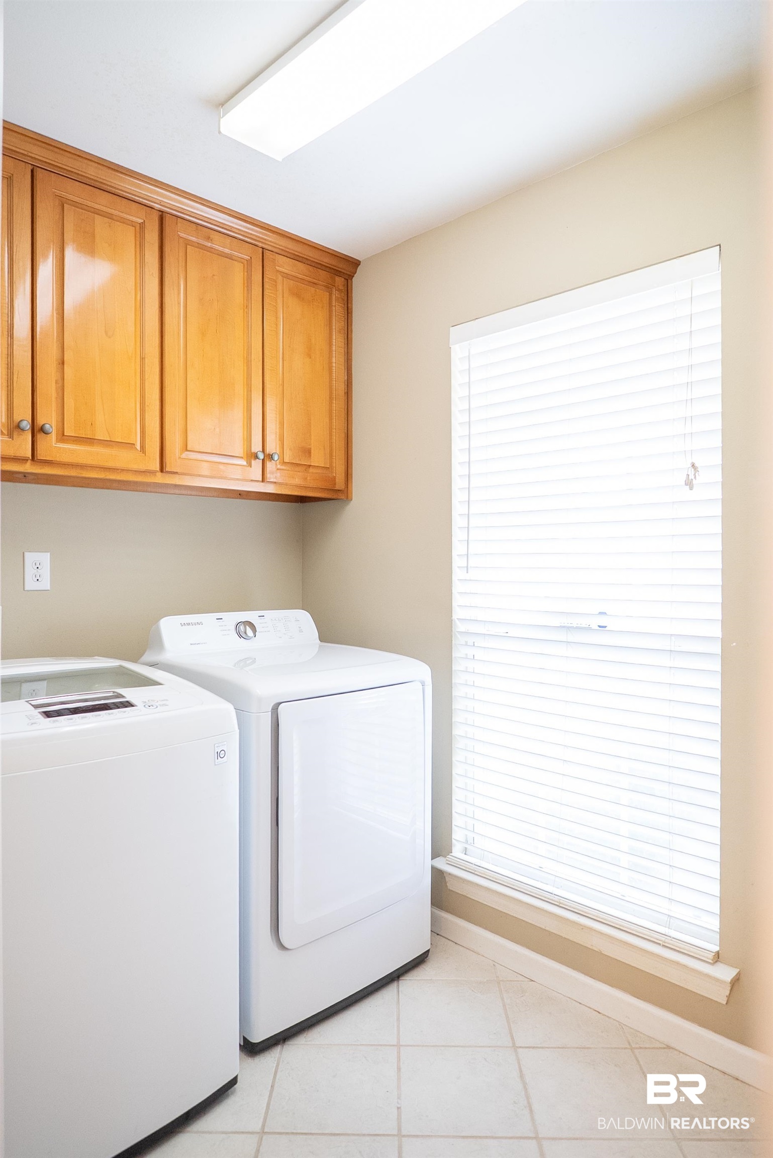 10023 Springfield Court Mobile, AL 36695 - Photo 20 of 50 Laundry area featuring washer and clothes dryer, light tile patterned floors, and cabinet space