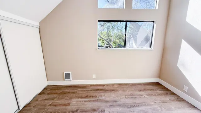 a view of an empty room with wooden floor and a window