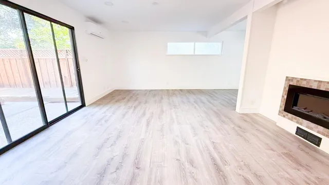 a view of empty room with wooden floor and fireplace