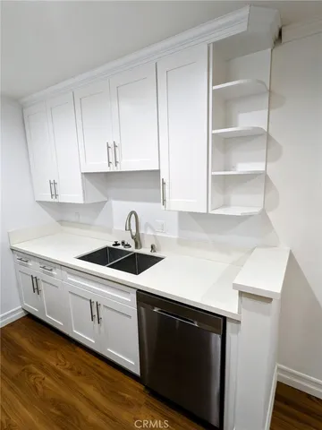 a kitchen with stainless steel appliances a sink dishwasher a stove and white cabinets with wooden floor