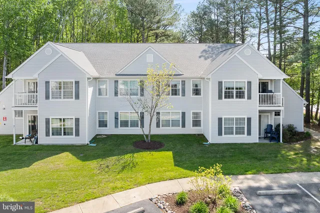 a view of a white house next to a yard with big trees