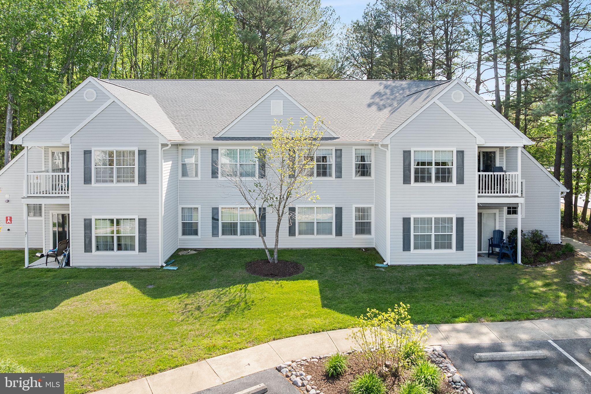 11431 Manklin Creek Road, Unit 5 Berlin, MD 21811 - Photo 1 of 38 a view of a white house next to a yard with big trees