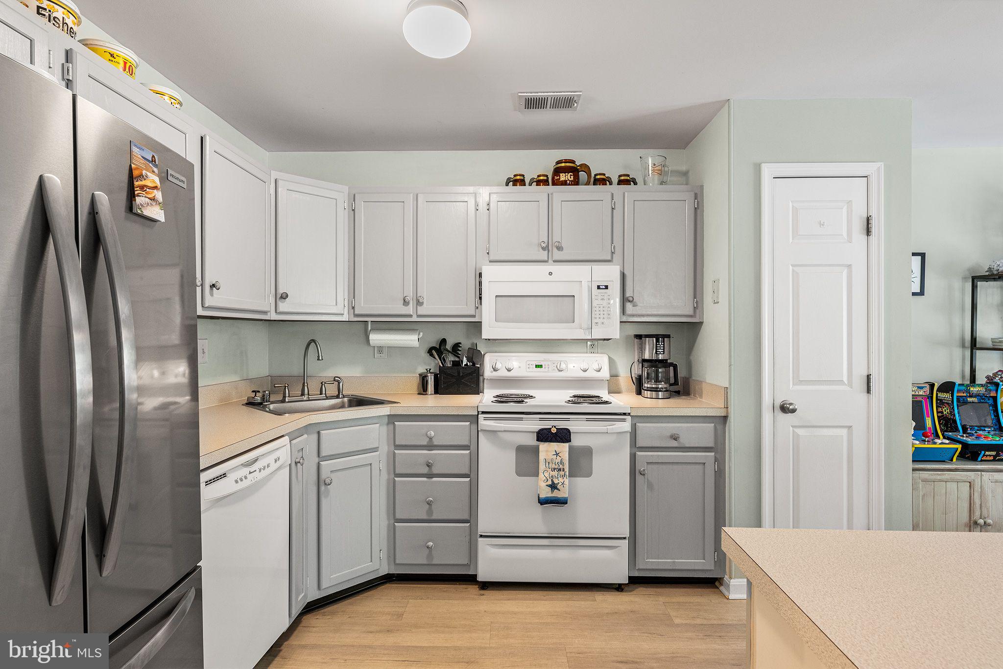11431 Manklin Creek Road, Unit 5 Berlin, MD 21811 - Photo 11 of 38 a kitchen with white cabinets and white appliances