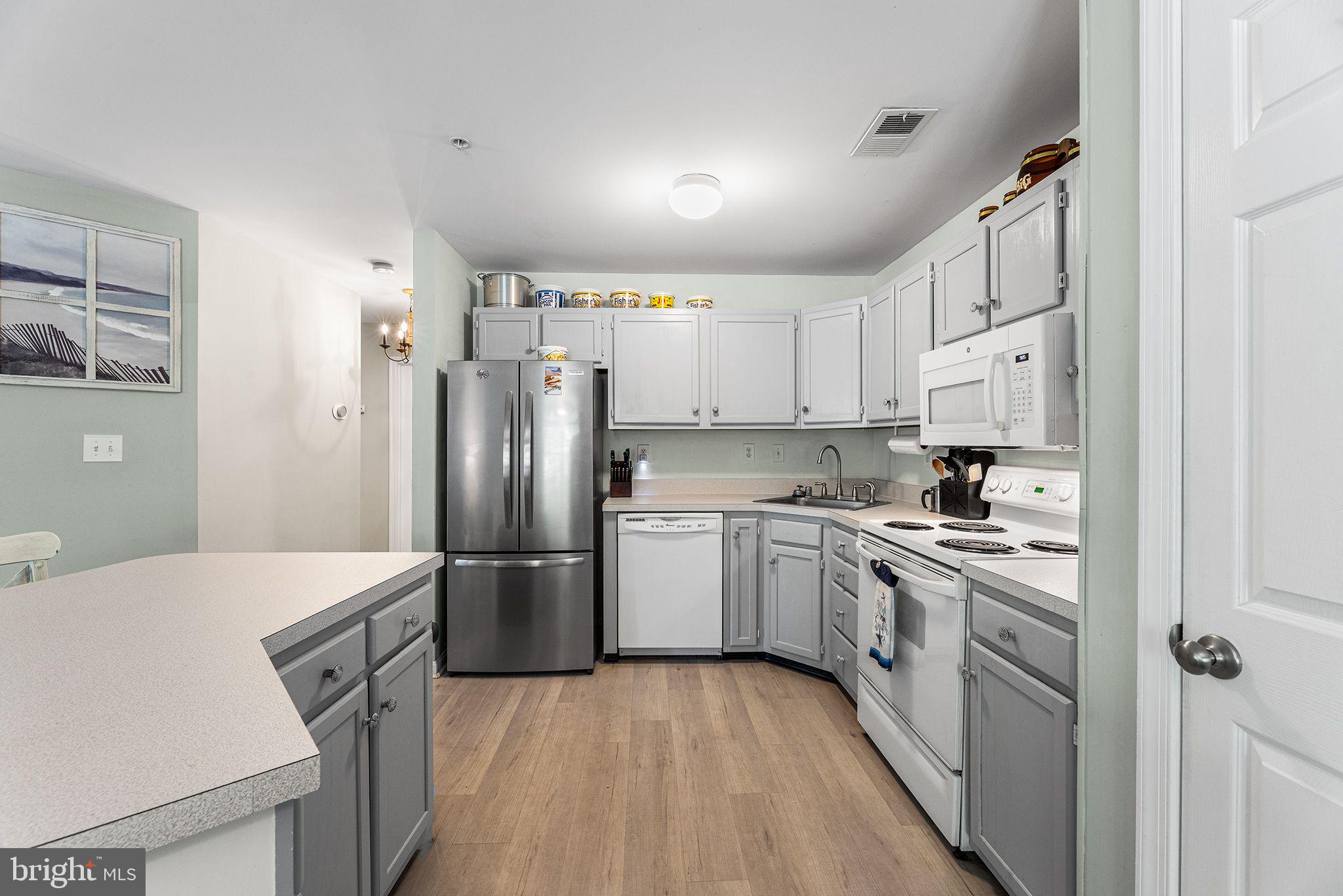 11431 Manklin Creek Road, Unit 5 Berlin, MD 21811 - Photo 13 of 38 a kitchen with a sink a refrigerator a stove and white cabinets