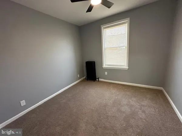 an empty room with chandelier fan and windows