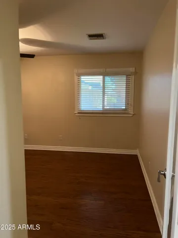 an empty room with wooden floor fan and windows