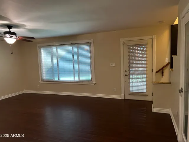 a view of an empty room with a window and wooden floor