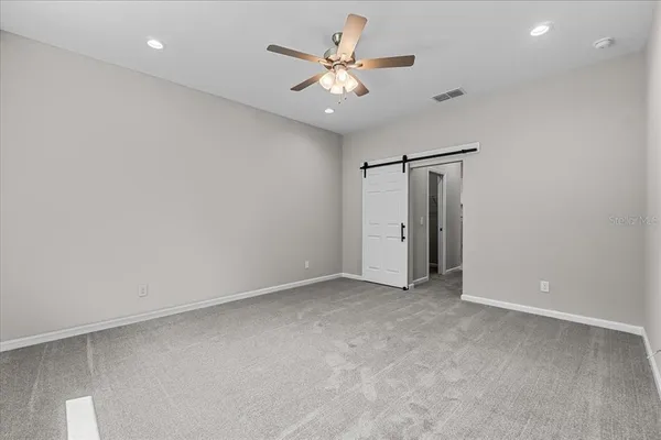 an empty room with closet and a ceiling fan