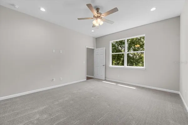 an empty room with a window and a ceiling fan