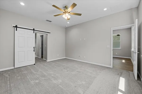an empty room with closet and a ceiling fan