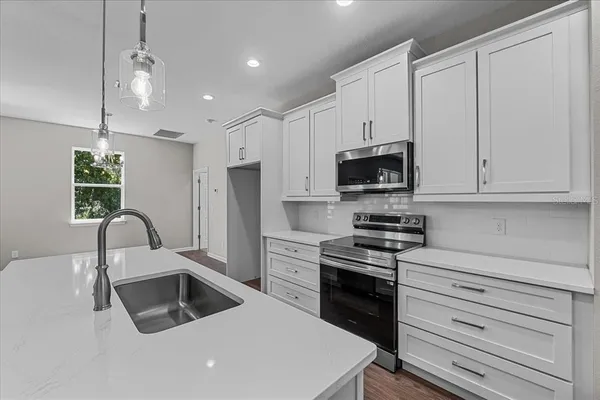 a kitchen with granite countertop white cabinets and stainless steel appliances