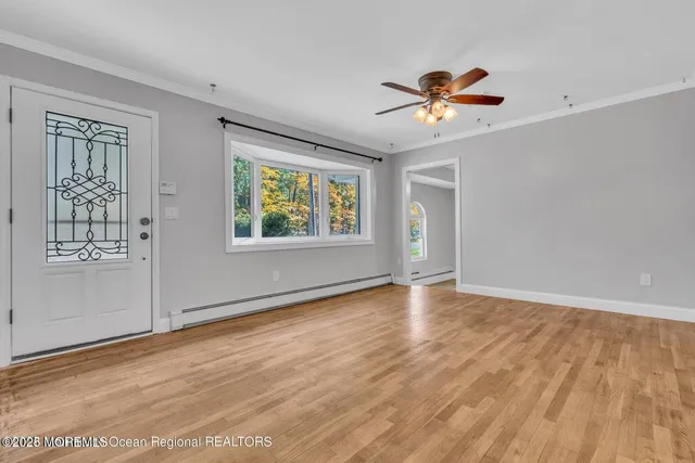 a view of an empty room with a window and wooden floor