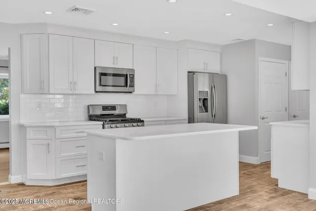 a kitchen with stainless steel appliances white cabinets and a stove top oven