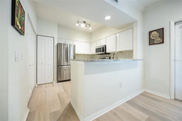 a kitchen with granite countertop a sink stainless steel appliances and white cabinets