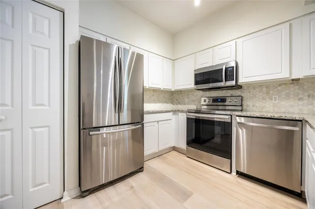 a kitchen with granite countertop white cabinets stainless steel appliances and a sink