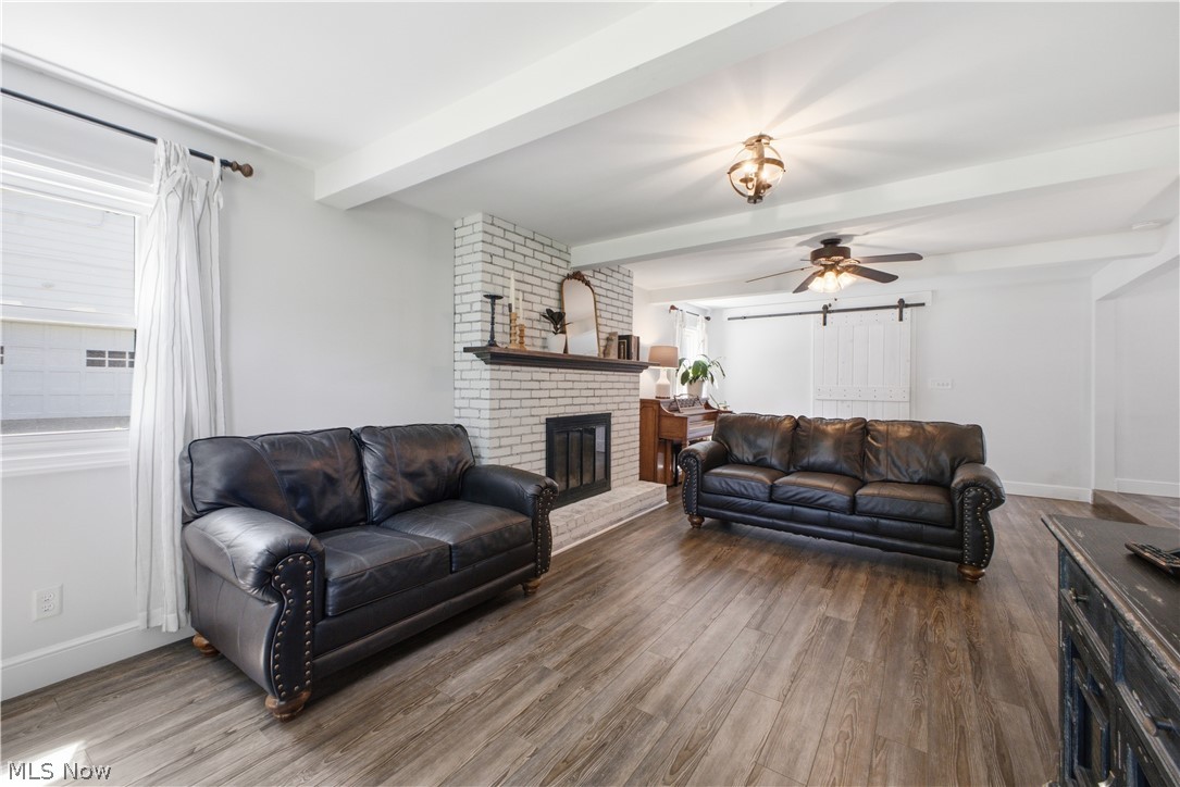 2411 Ridgeview Lane Youngstown, OH 44514 - Photo 13 of 48 Spacious living area featuring a white brick fireplace with dark wood mantel, wood-finish flooring, and white exposed ceiling beams