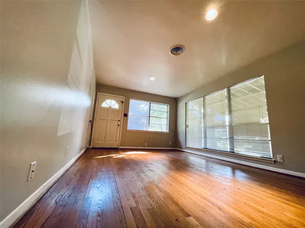 a view of empty room with wooden floor and fan